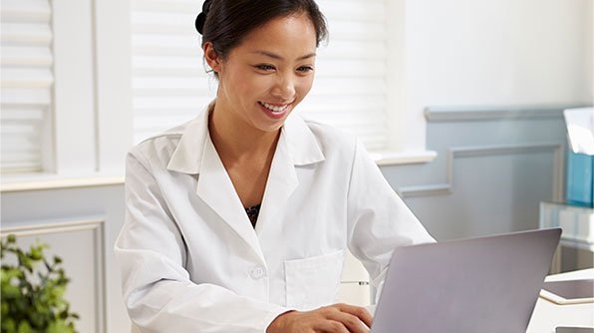 Seated provider smiling at laptop